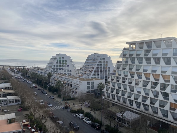 Un edificio moderno con una facciata geometrica unica, situato vicino a una strada con auto e pedoni.