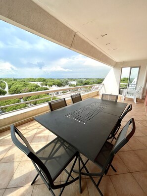 Un balcone con tavolo e sedie, con vista su un paesaggio verde e degli edifici.