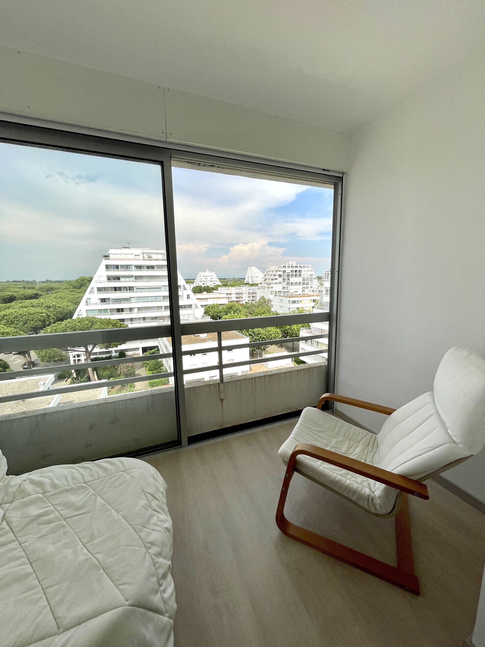 Une chambre moderne avec une grande fenêtre, une chaise blanche et un lit.