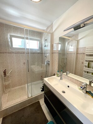 Un bagno moderno con doccia vetrata, un ampio lavabo con specchio e un porta asciugamani.