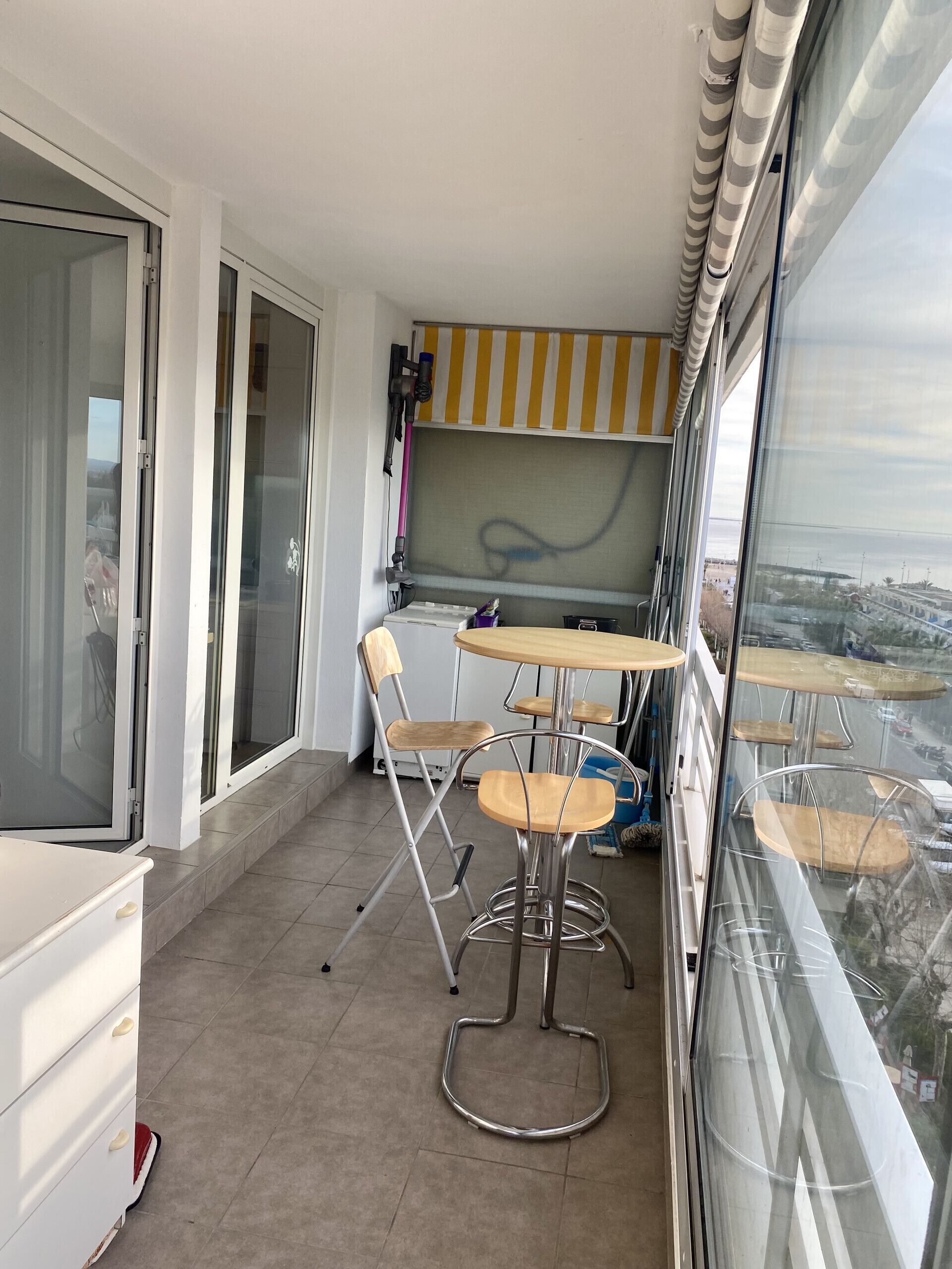 Un balcon doté d’un espace repas, comprenant une table et des chaises, et offrant une vue sur le paysage urbain.