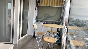 Un balcon doté d’un espace repas, comprenant une table et des chaises, et offrant une vue sur le paysage urbain.