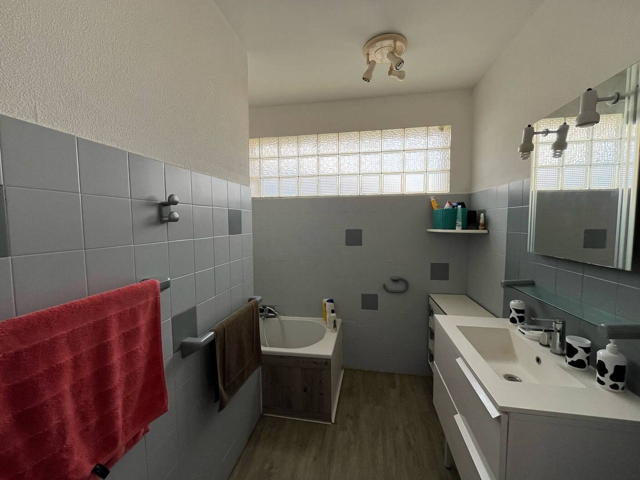 A bathroom with a bathtub, a sink, a mirror, and a window.