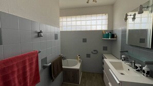 A bathroom with a bathtub, a sink, a mirror, and a window. - Quartier des Goélands, Villa t5 pour 8 N25 (La Grande-Motte)