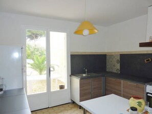 A kitchen with a white countertop, a sink, and a yellow pendant light.
