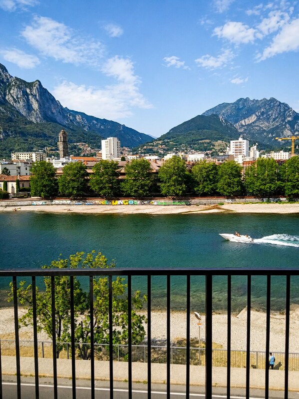 A coastal town with a river, mountains, and a view from a balcony with a railing.