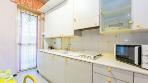 Une cuisine de taille réduite avec des meubles blancs, un four à micro-ondes et un petit évier.