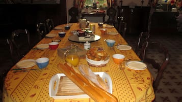 Een eettafel gedekt met borden, kommen, een karaf en een mand met brood.