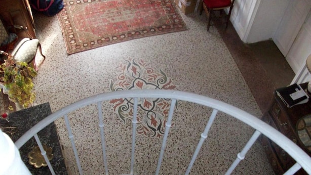 A spiral staircase with a patterned carpet and a chair in the background.