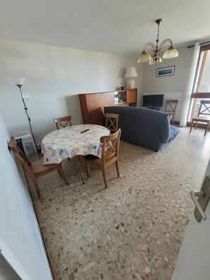 Ein gemütlicher Wohnraum mit Esstisch, Stühlen, einer Couch, einem Fernseher und einer Lampe.