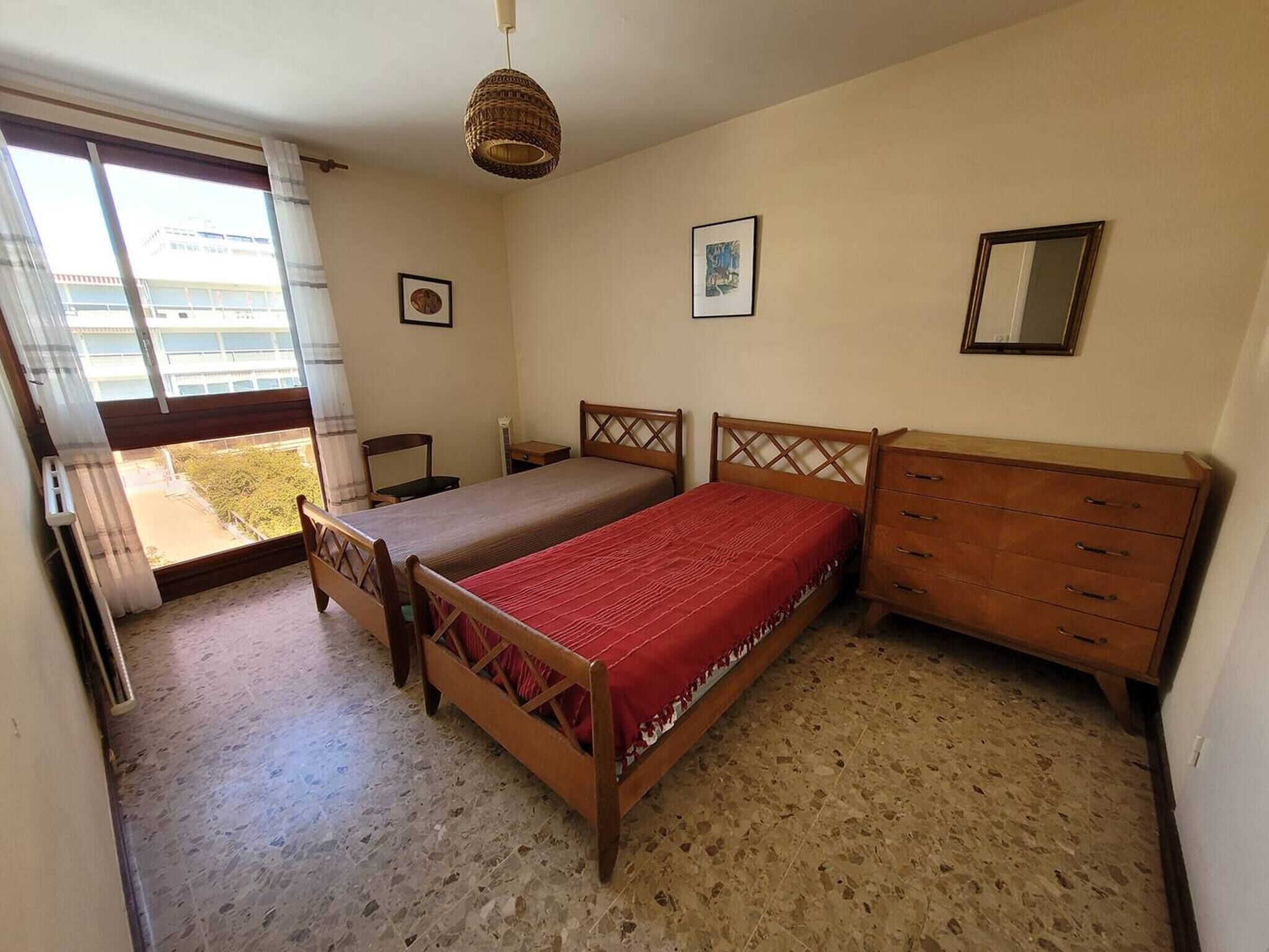 Une chambre à coucher avec un lit, une commode, une chaise et une fenêtre.