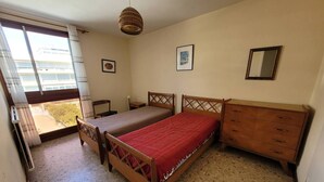 A bedroom with a bed, a dresser, a chair, and a window. - Coeur de ville, t3 pour 6 personnes N35 (La Grande-Motte)