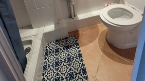A bathroom with a white sink, a mirror, a toilet, and a patterned floor mat. - Quartier du port, t4 pour 8 personnes N12 (La Grande-Motte)