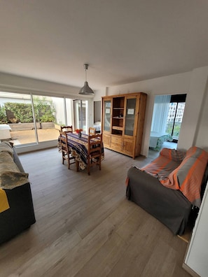 Een ruime woonkamer met een eettafel, een houten kast en een bank.