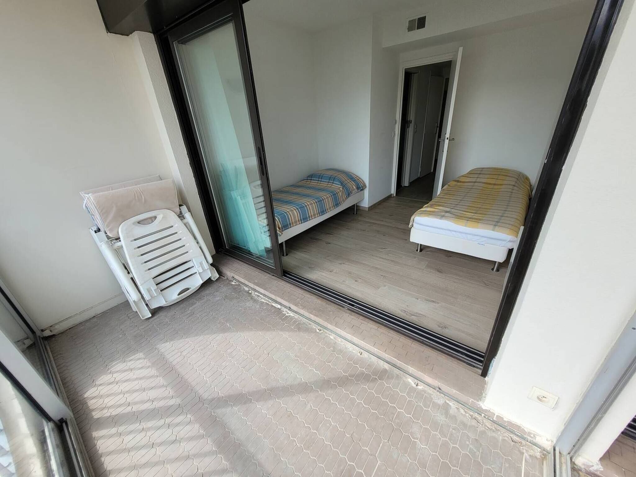 Een kleine, compacte kamer met twee bedden, een schuifdeur en een radiator.