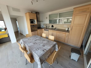 Een moderne keuken met houten kastjes, een eettafel met stoelen en uitzicht op het omliggende landschap.