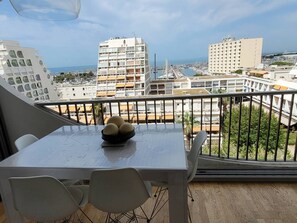Ein Balkon mit Tisch und Stühlen mit Blick auf einen Yachthafen mit Booten und Gebäuden.