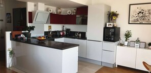 Una cocina moderna con una isla central, muebles blancos y una pared de acento roja.
