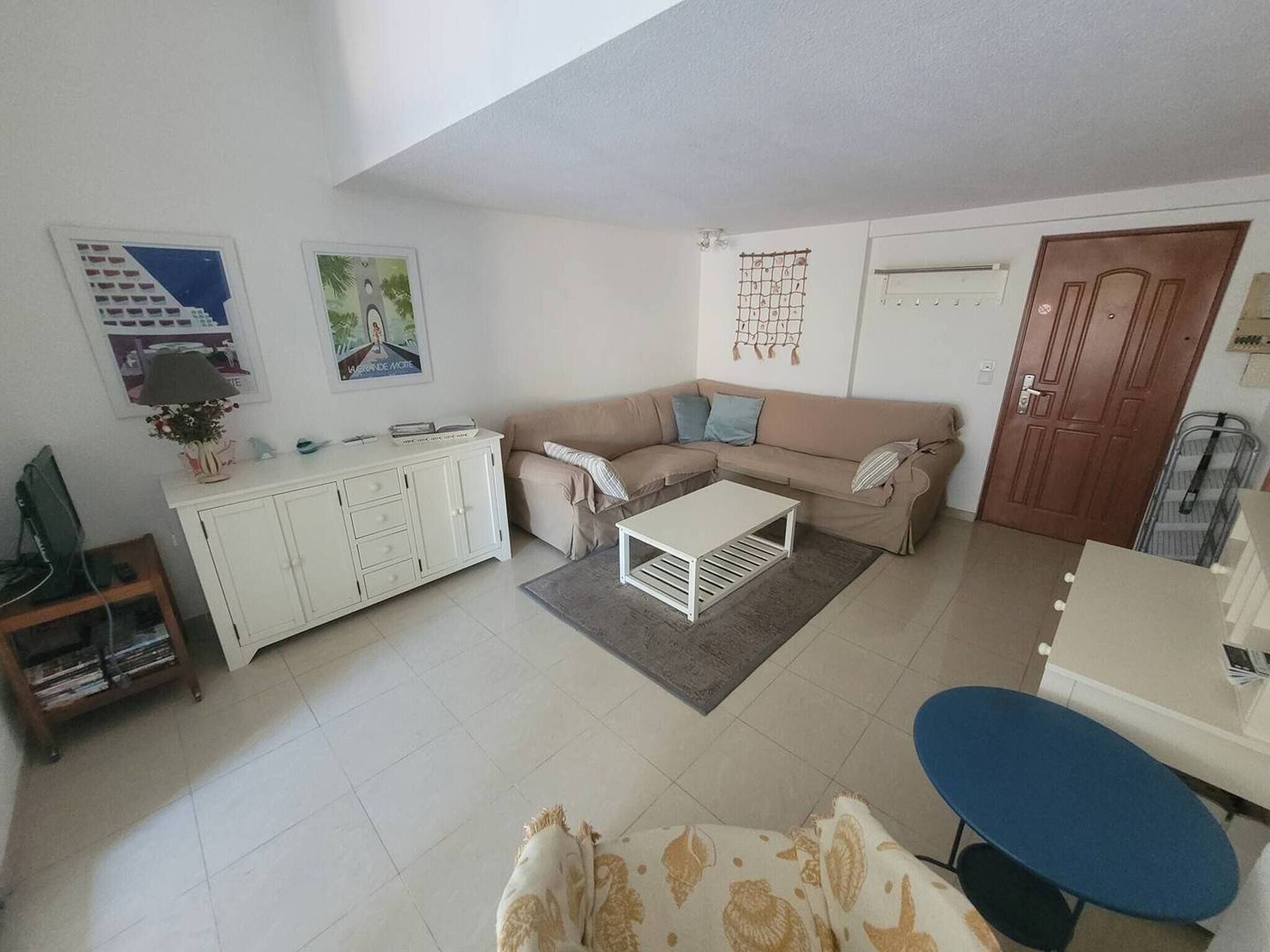A living room with a sofa, a coffee table, a TV, and a bookshelf.