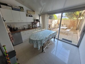 A kitchen with a dining area, white cabinets, a microwave, and a table with a patterned tablecloth. - Au centre de la Grande Motte, t3 pour 5 N24 (La Grande-Motte)