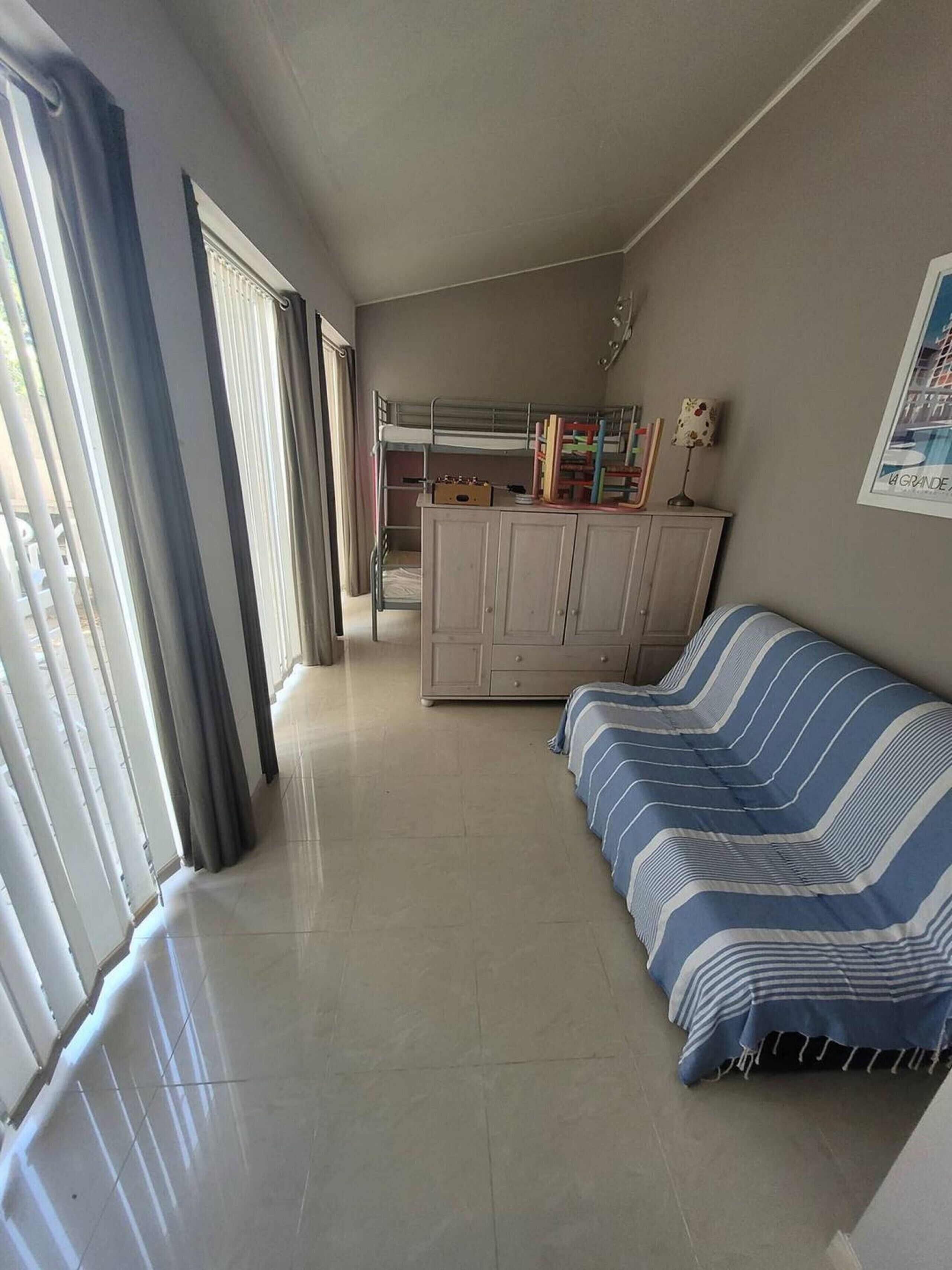 A room with a sofa, a cabinet, and a window with curtains.