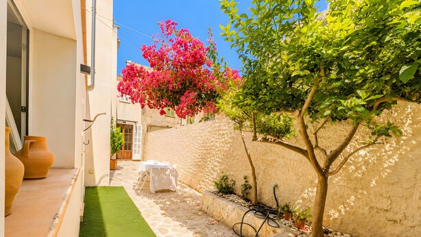 A narrow outdoor space with a white wall, a small tree, a white table, and a green artificial turf. - Ca na Victòria: Mallorcan Home with Wi-Fi and Air Conditioning (Santa Margalida)