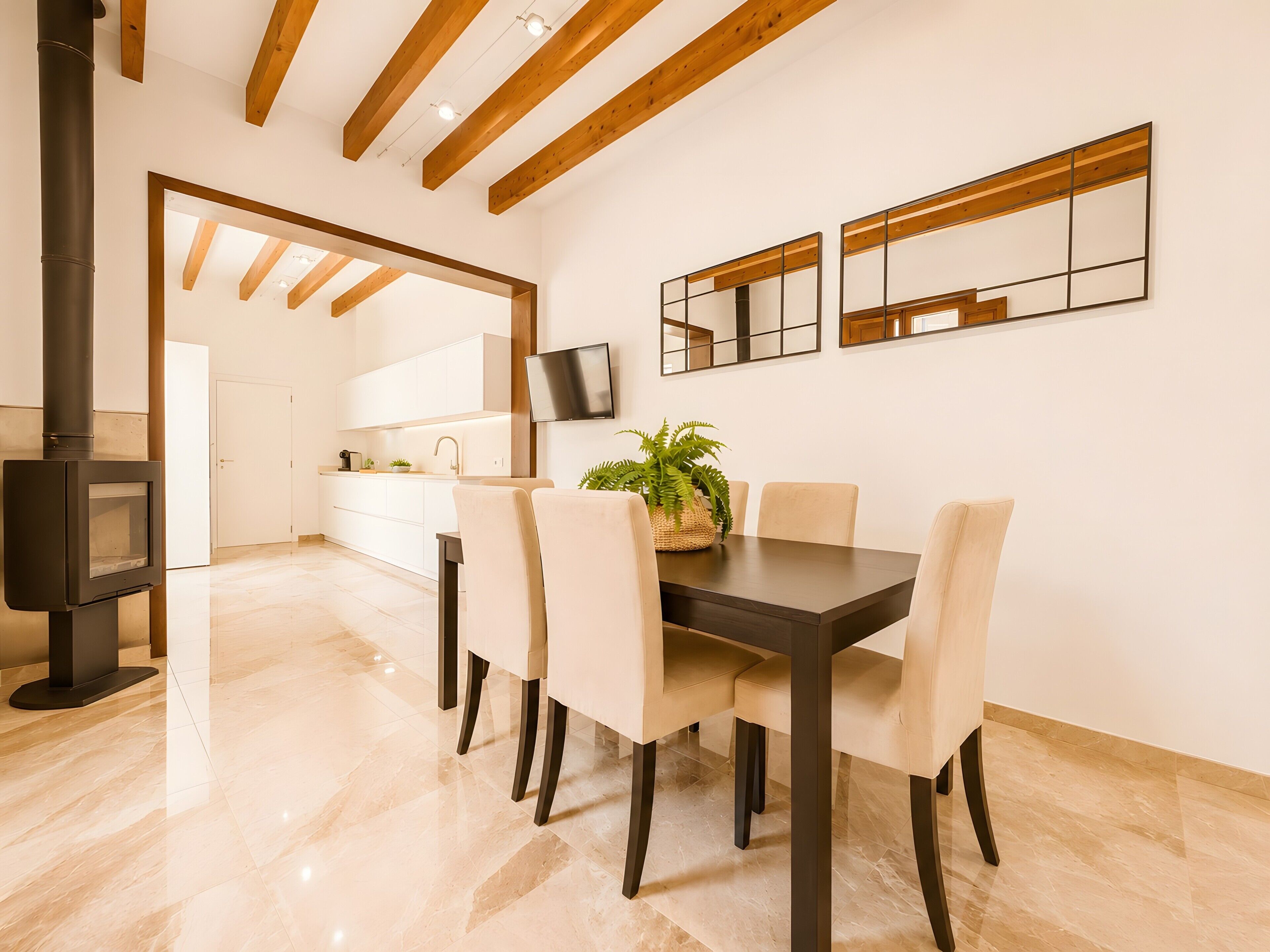 A modern kitchen with white cabinets, a dark wood table, and chairs.