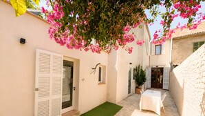 A courtyard with a table, a door, and a potted plant. - Ca na Victòria: Mallorcan Home with Wi-Fi and Air Conditioning (Santa Margalida)