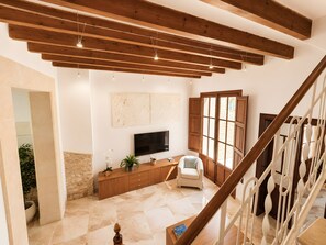 Un espai saló ampli amb sostre alt, bigues de fusta, televisió de pantalla plana, zona de seients confortable i vista per una finestra gran.