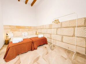 A hotel room with a bed, a hanging clothes rack, a nightstand, and a lamp. - Ca na Victòria: Mallorcan Home with Wi-Fi and Air Conditioning (Santa Margalida)