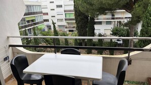 Un balcone con tavolo e sedie, affacciato su una zona residenziale con edifici e alberi.
