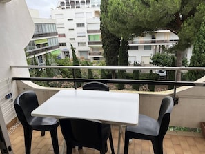 Un balcó amb taula i cadires, amb vista a una zona residencial amb edificis i arbres.