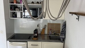 Una cucina compatta con un tavolo da pranzo in vetro, mobili bianchi e un forno a microonde integrato.