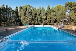 A rectangular swimming pool with a tiled edge, surrounded by a wooden deck.