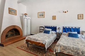 A bedroom with two beds, a fireplace, and a wardrobe.