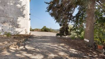 A gravel path leading to a white building with a sign reading 'ACCESO' and a tree with a sign 'ACCESO' on its trunk.
