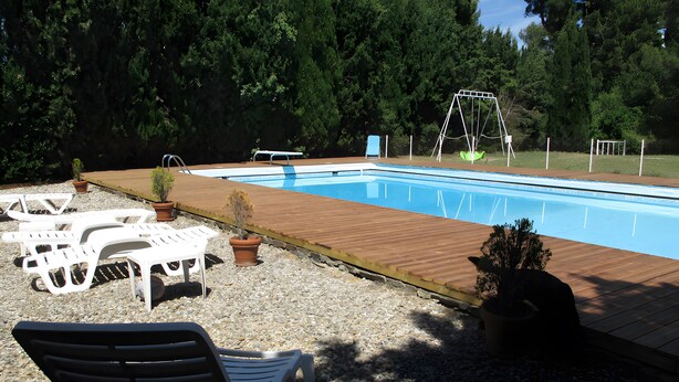 A swimming pool with a wooden deck, lounge chairs, and a swing set. - Bed and Breakfast 'Chambre Rolland' with Shared Pool, Shared Garden and Wi-Fi (Carcassonne)