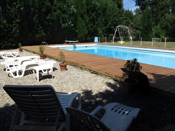 A swimming pool with a wooden deck, lounge chairs, and a swing set. - Bed and Breakfast 'Chambre Rolland' with Shared Pool, Shared Garden and Wi-Fi (Carcassonne)