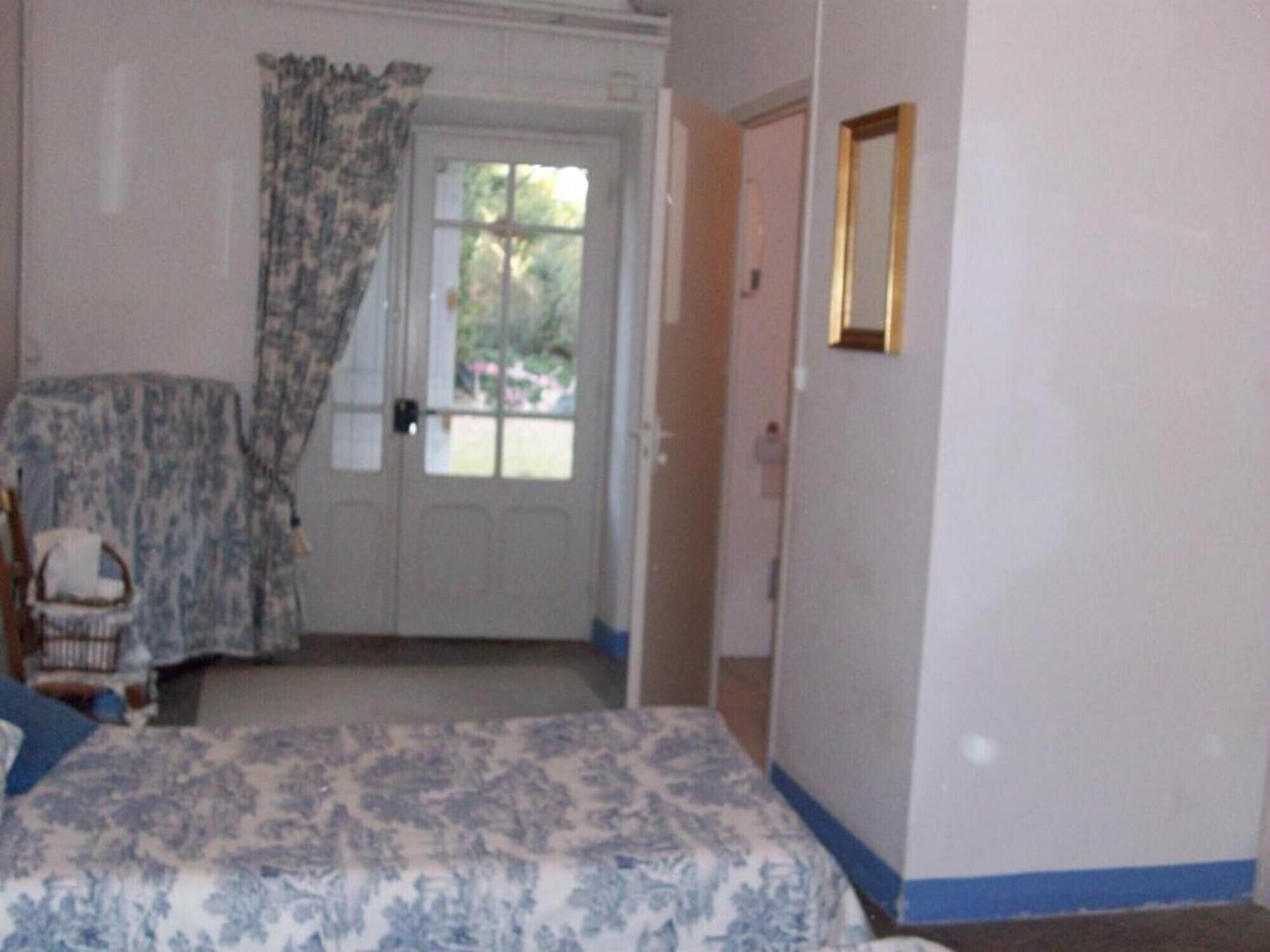 Een slaapkamer met een bed, een stoel, een deur en een raam.