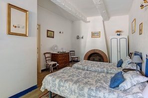 A bedroom with a bed, dresser, chair, fireplace, and wall-mounted lights. - Bed and Breakfast 'Chambre Rolland' with Shared Pool, Shared Garden and Wi-Fi (Carcassonne)