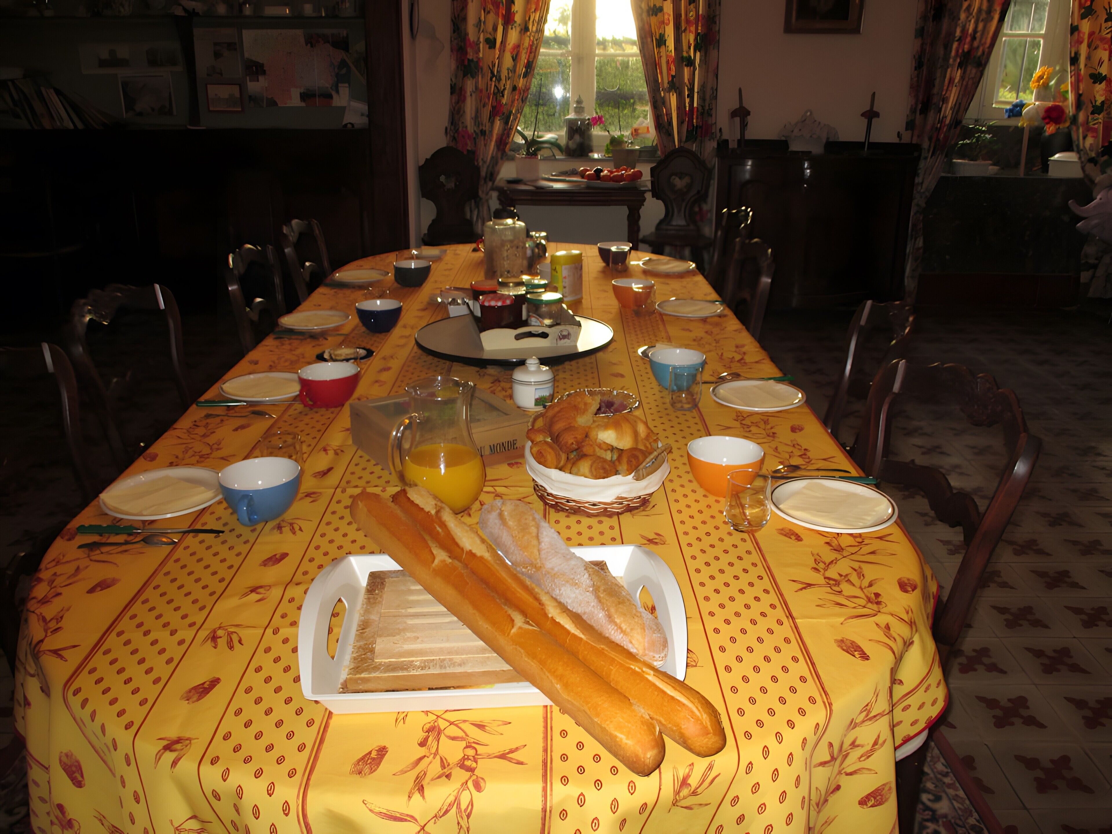 Een eettafel gedekt met borden, kommen, een karaf en een mand met brood.