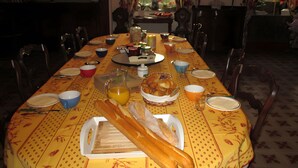 A dining table set with plates, bowls, a pitcher, and a basket of bread. - Bed and Breakfast 'Chambre Rolland' with Shared Pool, Shared Garden and Wi-Fi (Carcassonne)