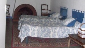 A bedroom with a bed, a fireplace, a chair, and a small table. - Bed and Breakfast 'Chambre Rolland' with Shared Pool, Shared Garden and Wi-Fi (Carcassonne)