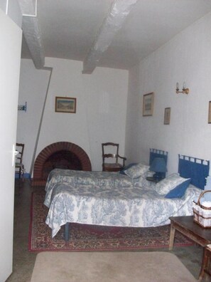 A bedroom with a bed, a fireplace, a chair, and a small table. - Bed and Breakfast 'Chambre Rolland' with Shared Pool, Shared Garden and Wi-Fi (Carcassonne)