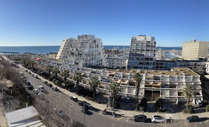 A coastal hotel complex with multiple buildings, a marina, and a clear view of the sea.