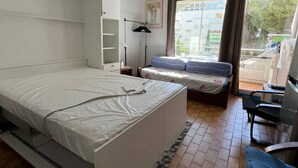 Quarto com cama, escrivaninha, cadeira e janela com cortinas.