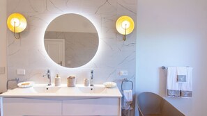 Een badkamer met een grote spiegel, twee wastafels en twee wandlampen.