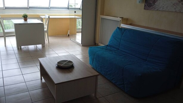 A room with a blue sofa, a small wooden table, and a white chair. - Première ligne Plage, studio pour 2 N20 (La Grande-Motte)