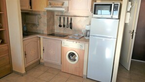 A compact kitchen with a washing machine, a microwave, and a sink. - Première ligne Plage, studio pour 2 N20 (La Grande-Motte)