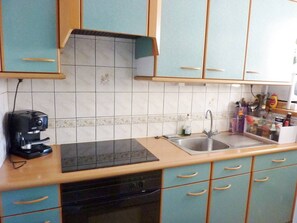 A kitchen with teal cabinets, a black stove, and a sink. - Première ligne Mer, t3 duplex pour 6 N05 (La Grande-Motte)